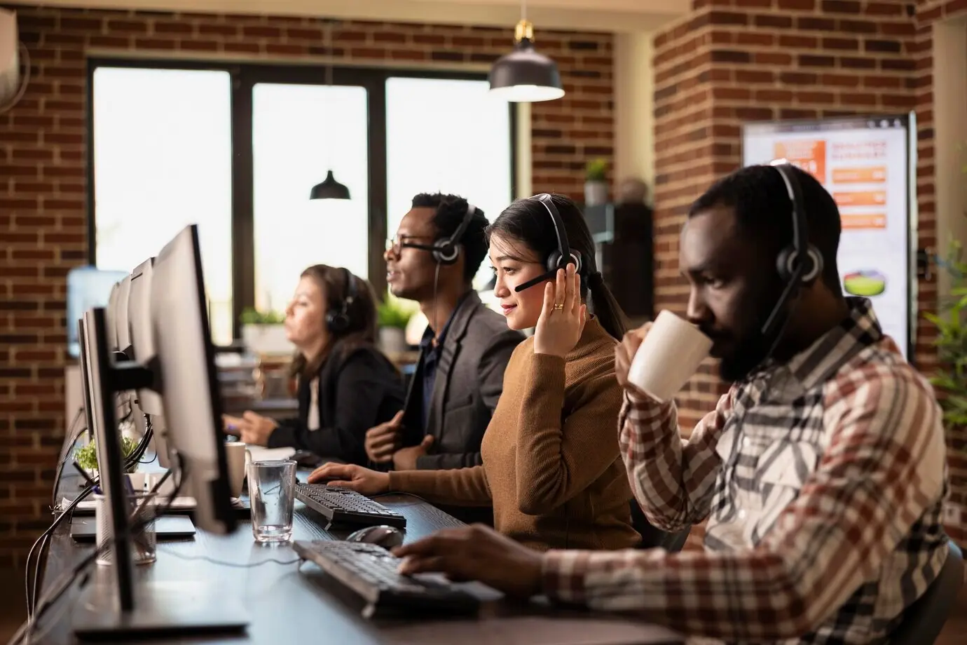 Verschiedene Telemarketer sitzen im Büro.